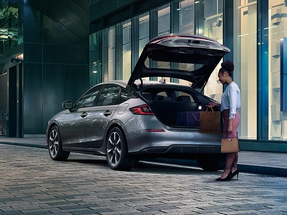 2026 Honda Civic Hatchback Sport Touring Hybrid in Solar Silver Metallic back parked on a city street with the hatch open (Compact Hatchback).